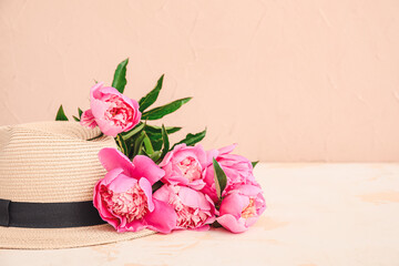 Beautiful peony flowers and hat on table