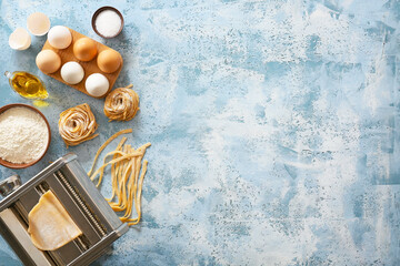 Obraz na płótnie Canvas Pasta machine with ingredients on color background