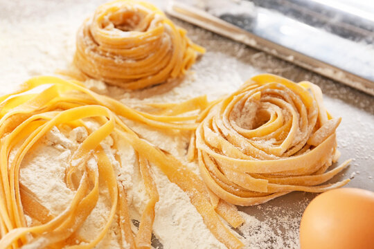 Raw pasta with flour and egg on table