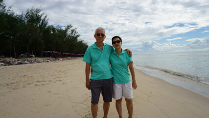 Asian elder senior couple standing together at beach front happy retirement life