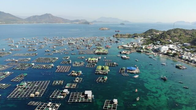 Aerial view of Binh Hung island with tourists, fishing boats, fishing villages and floating rafts raising seafood in Ninh Thuan province, Vietnam