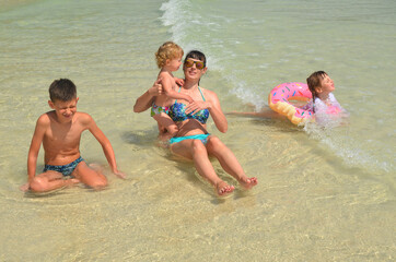 Happy family having fun. Mother and her children swimming in the sea in summer vacation lifestyle