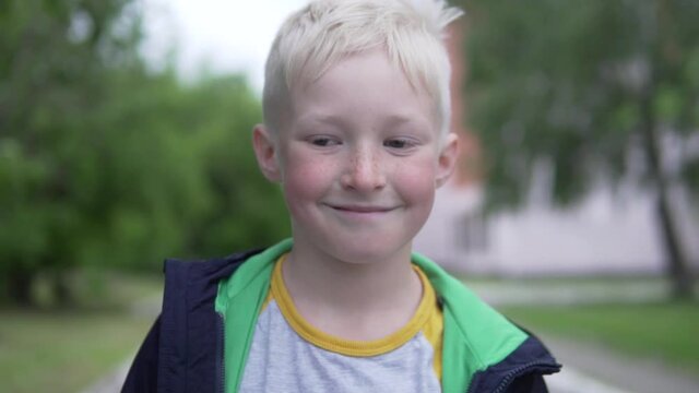 A close-up of the face of a handsome teenage albino boy on a walk after self-isolation.