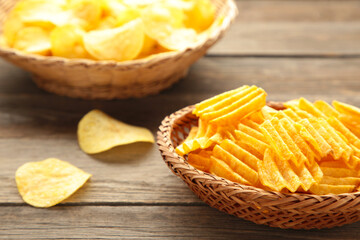 Potato chips in basket on grey wooden background.