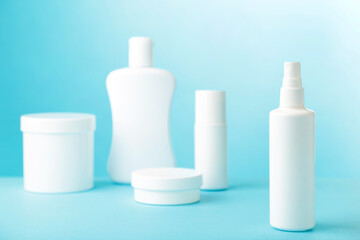 White cosmetic bottles on blue background. Top view
