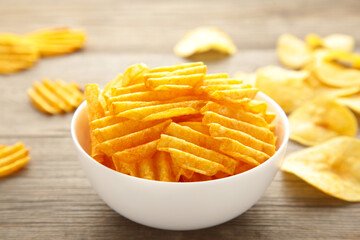 Potato chips on white bowl on grey wooden background