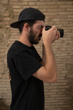 Chico tatuado con c&aacute;mara de fotos haciendo una foto