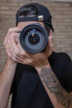 Chico tatuado con c&aacute;mara de fotos haciendo una foto