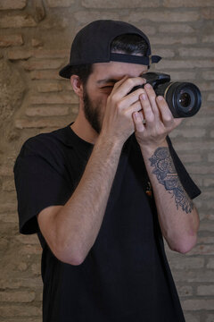 Chico tatuado con c&aacute;mara de fotos haciendo una foto