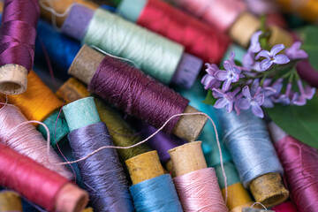 reels with multicolored threads of natural silk and a small lilac inflorescence, close-up