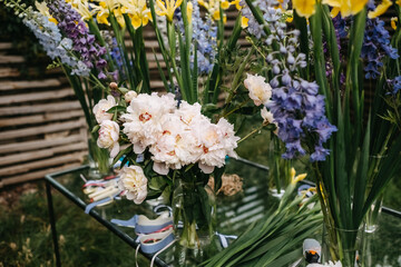 Bouquet of spring flowers in a glass vase. Bouquet of pale pink peonies and yellow iris flowers.