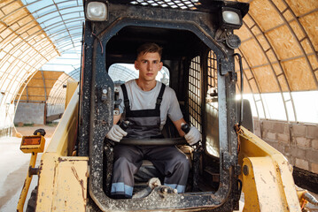 Fototapeta na wymiar A man in overalls driving a tractor. Worker sitting on his tractor