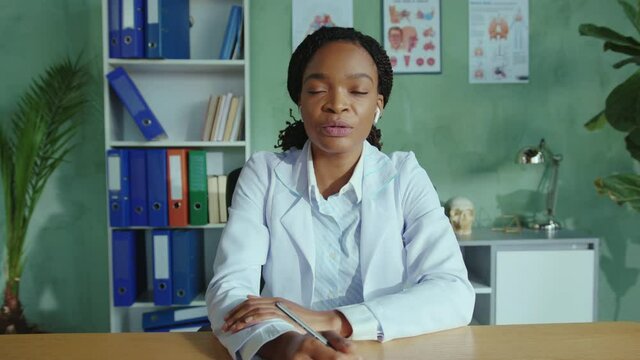 Friendly nice young female doctor in earphones consulting a remote patient via webcam chat video conference and giving advice instructions for healing. Telemedicine concept.