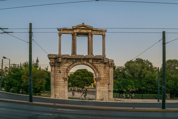 Arch-shaped marble-made Hadrian's Arch in front of a modern city road in Athens