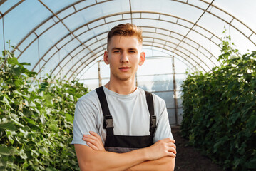 Obraz premium Portrait of a young male farmer in overalls in a greenhouse