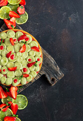 Round fruit tart cake with strawberries. pistachios and lime on the wooden cut board