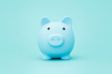 Blue piggy bank on blue background space for text. Savings concept.
