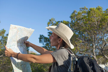 A woman hiking in the mountains of Majorca. A hiker looking at the map while traveling on the island of majorca. The girl is wearing a hat and an Australian look, has long hair and two braids.