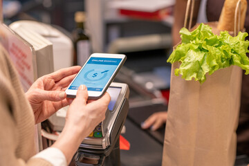 Hands of contemporary mature customer with smartphone over payment machine