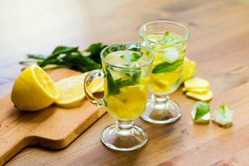 Two glasses with a homemade drink of lemon, mint and ginger