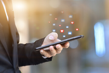 Close-up of businessman hands using mobile smartphone with social media icon. Idea for business, online marketing and technology.