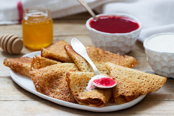 Rye and whole grain pancakes served with sour cream, honey and strawberry sauce. Rustic style.