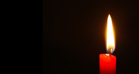 Red candle burning on black background. Long banner with copy space