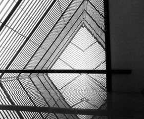 Black and white picture of a massive metallic structure who looks like the inside of a pyramid. You may see the reflection on the right side.