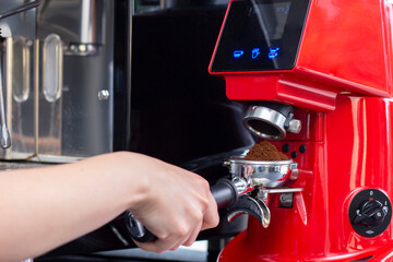 Close up shot of professional bartender preparing espresso coffee in exclusive cafe bar or cafeteria. He using coffee mill or grinder.