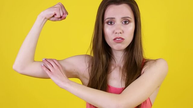Upset displeased woman looks at her biceps and expresses extreme discontent and anger. People sincere emotions, lifestyle concept.