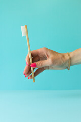 organic white bamboo toothbrush in hand on blue background. Copy space, dental care concept.