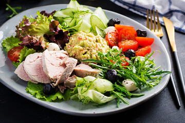 Ketogenic diet. Dinner dish with boiled pork meat, avocado guacamole, tomatoes, cucumbers, mozzarella cheese, black olives  and arugula. Detox and healthy concept. Keto food.