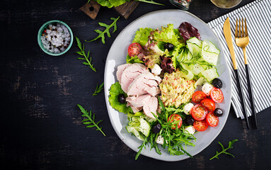 Ketogenic diet. Dinner dish with boiled pork meat, avocado guacamole, tomatoes, cucumbers, mozzarella cheese, black olives  and arugula. Detox and healthy concept. Keto food. Overhead, top view