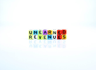 Conceptual of unearned revenues in  financial statements. Colorful alphabet beads isolated over reflective white surface. Focus of text R at center. Others in gradient blur.