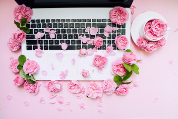 Postcard template. The laptop keyboard is strewn with flowers, a white cup pink background. Valentine's Day. Women's Day. Festive background. Morning concept. Flat lay