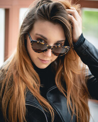 Naklejka premium Modelo pelirroja con gafas de sol y chaqueta de cuero