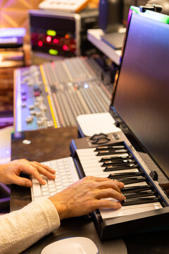 male producer, composer hands arranging music on keyboard and computer in home recording studio. music production concept