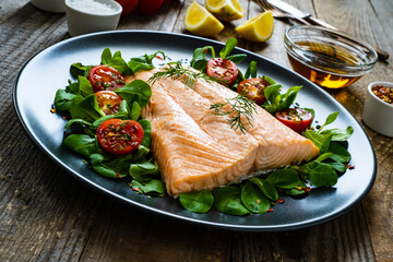 Steamed salmon fillet with vegetables on wooden table
