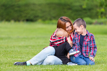 Cute cheerful two  boys brother child with mother play outdoors in park. Happiness and harmony of family life. Great family vacation. Mother and son have activities together on holidays.
