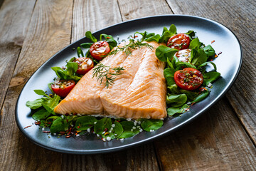 Steamed salmon fillet with vegetables on wooden table
