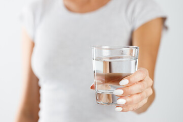 A woman holds a glass of water in her hands. Healthy lifestyle concept.