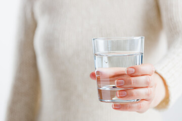 A woman holds a glass of water in her hands. Health care concept.