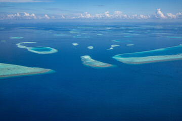 Naklejka na ściany i meble Aerial view of Maldives atolls is the world top beauty. Maldives tourism. Luxury travel destination, amazing nature environment, islands atoll and coral reef. Tropical landscape, aerial view