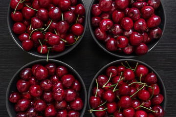 Two varieties of cherries lies in dark plates on a dark background