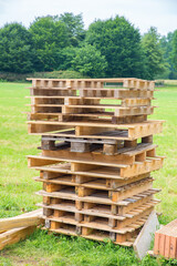 High pile of wooden pallets in meadow