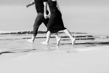 young couple a guy with a girl in black clothes are walking on the white sand