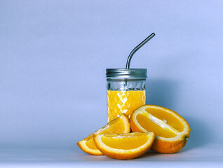 refreshing orange juice in a glass cup with a metal tube and orange on a blue background