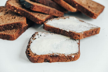 Sliced of brown bread with butter on a white wooden background. Top view. Copy, empty space for text