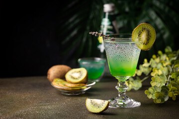 Cold cocktail kiwi drink in a glass with fresh fruits on black background
