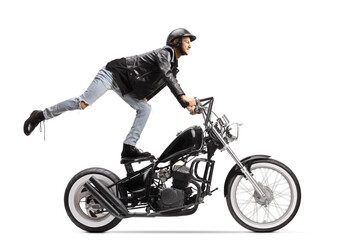 Fototapeta na wymiar Daredevil biker standing on the seat and riding a chopper motorbike
